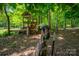 A curious goat stands in the foreground, near a wooden playhouse, amidst lush foliage and natural beauty at 174 Buena Vale Dr, Gastonia, NC 28056