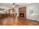 Spacious living room featuring hardwood floors, a classic brick fireplace, and an open doorway to the kitchen at 174 Buena Vale Dr, Gastonia, NC 28056