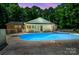 A backyard pool sparkles as twilight sets, surrounded by lush greenery and the home's charming exterior at 174 Buena Vale Dr, Gastonia, NC 28056