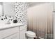 Modern bathroom showcasing a black and white aesthetic, updated fixtures and stylish wallpaper at 2635 Mccurdy Trl, Charlotte, NC 28269