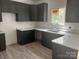 Modern kitchen with sleek, dark cabinetry, white countertops, and stainless steel sink and hardwood floors at 3137 Riber Ln, Claremont, NC 28610