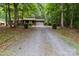 Home with long gravel driveway, garage, and front porch, surrounded by mature trees and lush greenery at 503 Overbrook Dr, Albemarle, NC 28001
