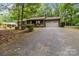 Home with long gravel driveway, garage, and front porch, surrounded by mature trees and lush greenery at 503 Overbrook Dr, Albemarle, NC 28001