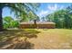 Large backyard with well-maintained lawn, brick home, and tall trees at 6215 Simpson Rd, Charlotte, NC 28216