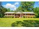 Charming brick home with a manicured lawn and lush landscaping under a sunny, blue sky at 6215 Simpson Rd, Charlotte, NC 28216