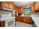 Galley kitchen featuring wood cabinets, white appliances, and a window over the sink at 6215 Simpson Rd, Charlotte, NC 28216