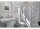 Well-lit bathroom featuring a pedestal sink, toilet, and shower with a decorative curtain at 7648 Forest Oak Dr, Denver, NC 28037