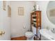 Compact half bath with wood floors, pedestal sink, and decorative shelving unit at 8414 Oak Ne Dr, Charlotte, NC 28269