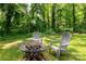 Secluded backyard featuring a fire pit with chairs, surrounded by lush greenery and mature trees at 981 Sherwood Cir, Lancaster, SC 29720
