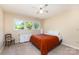 Bright bedroom features a ceiling fan, three windows, and neutral carpeting at 103 Sadler Rd, Mount Holly, NC 28120