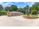 Brick ranch-style home featuring a spacious driveway, manicured lawn, and mature trees under a sunny sky at 103 Sadler Rd, Mount Holly, NC 28120