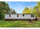 Back of a white siding home with a brick foundation, windows, and a green lawn at 1055 Cedar Hill Dr, Rockwell, NC 28138
