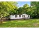 Exterior of a white siding home with a porch, deck, and green lawn in a wooded setting at 1055 Cedar Hill Dr, Rockwell, NC 28138