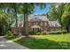 Stately brick home features mature trees, manicured lawn, and classic architectural details at 12048 Royal Portrush Dr, Charlotte, NC 28277