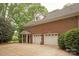 Three car garage exterior with a brick facade and a well-maintained driveway and landscaping at 12048 Royal Portrush Dr, Charlotte, NC 28277