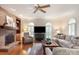 Living room features brick fireplace, built-ins, a ceiling fan, plantation shutters, and hardwood flooring at 12048 Royal Portrush Dr, Charlotte, NC 28277