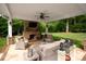 Inviting covered patio with a stone fireplace, comfortable seating, and serene backyard views at 12048 Royal Portrush Dr, Charlotte, NC 28277