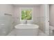 Stylish bathroom features a soaking tub, marble tile, and a bright window at 1208 Tarrington Ave, Charlotte, NC 28205