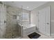 Modern bathroom featuring a walk-in shower with decorative tile and a separate bathtub for a spa-like experience at 13315 Hunting Birds Ln, Charlotte, NC 28278