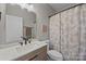Stylish bathroom features a marble countertop, modern faucet, and shower with floral shower curtain at 13315 Hunting Birds Ln, Charlotte, NC 28278