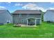 Manicured backyard with plush lawn, brick fire pit, and covered patio with comfortable outdoor furniture at 135 Canoe Pole Ln, Mooresville, NC 28117