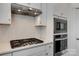 A modern kitchen cooktop with a stainless steel vent hood and backsplash at 1540 Striped Bass Ln, Clover, SC 29710