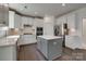 Bright kitchen with white cabinets, stainless steel appliances, gray island and hardwood flooring at 1540 Striped Bass Ln, Clover, SC 29710