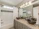 Bathroom with dual bowl sinks, tiled floors, gray cabinetry, subway tiled walls, and shower-tub combo at 3721 Providence Plantation Ln, Charlotte, NC 28270