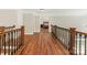 Upstairs hallway with hardwood floors, wood railing with metal spindles, and a view into one of the bedrooms at 3721 Providence Plantation Ln, Charlotte, NC 28270