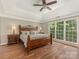 Comfortable main bedroom with tray ceiling, ceiling fan, large windows overlooking the outdoors, and hardwood floors at 3721 Providence Plantation Ln, Charlotte, NC 28270