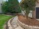 Landscaped side yard featuring decorative stone wall, pathway, and bordered by wood fence at 3721 Providence Plantation Ln, Charlotte, NC 28270