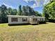 Single-story home with green roof, wooden porch, and purple window shutters, surrounded by trees and a grassy lawn at 668 Osteen Rd, York, SC 29745