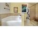 Bright bathroom featuring a tiled tub and a window at 7710 Grove Hall Ave, Mint Hill, NC 28227