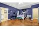 A spacious bedroom with wood flooring, purple walls, and ample space for a keyboard and artwork at 7710 Grove Hall Ave, Mint Hill, NC 28227