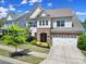 Front exterior of home with stone accents, lush landscaping, and a two-car garage on a sunny day at 1001 Emory Ln, Fort Mill, SC 29708