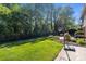Green backyard featuring lush lawn, mature trees, a stone fire pit area, basketball court, and a patio at 1002 4Th Ne St, Conover, NC 28613