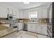 Well-lit kitchen featuring white cabinets, granite countertops, stainless steel appliances, and tile floors at 1002 4Th Ne St, Conover, NC 28613