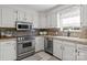 Well-lit kitchen features white cabinets, granite countertops, stainless steel appliances, and tile floors at 1002 4Th Ne St, Conover, NC 28613