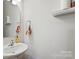 Clean half bathroom featuring a sink, mirror, and small storage shelf at 1206 Keydet Dr, Charlotte, NC 28216