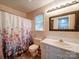 Bright bathroom featuring a white vanity, decorative shower curtain and a framed mirror at 145 Woodview Dr, Statesville, NC 28625
