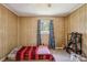 Cozy bedroom featuring wood paneling and a bright window with patterned curtains at 1975 Peace Rd, Fort Mill, SC 29715