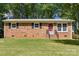 Well-kept brick home featuring a bright red front door, contrasted by green lawn and mature trees at 1975 Peace Rd, Fort Mill, SC 29715