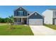 Two-story blue home featuring a manicured lawn and a two-car garage at 207 Giant Oak Ave, Statesville, NC 28677