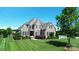 Stately two-story brick home boasts a lush green lawn, mature trees, and manicured landscaping for exceptional curb appeal at 3000 J R Ct, Stanley, NC 28164
