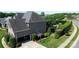 Aerial view of a brick home with an attached garage, well-maintained lawn, and a private backyard with mature trees at 3000 J R Ct, Stanley, NC 28164