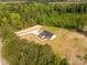 An aerial view showcasing the tan home's backyard, long drive, and surrounding green trees at 3650 Sentry Rd, Lancaster, SC 29720