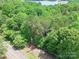 An aerial view of a wooded lot with a road and lake in the distance, offering privacy and natural beauty at 4585 Sunrise Beach Rd, Catawba, NC 28609