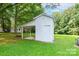 White shed with a covered area and a door in the backyard for storage or a hobby space at 4805 Nesbitt Rd, Monroe, NC 28112