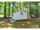 Quaint shed with unique window and covered area situated in a wooded yard at 4805 Nesbitt Rd, Monroe, NC 28112