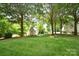 Serene backyard featuring a storage shed, lush green lawn, mature trees, and defined mulch beds at 5827 Rileys Ridge Rd, Charlotte, NC 28226